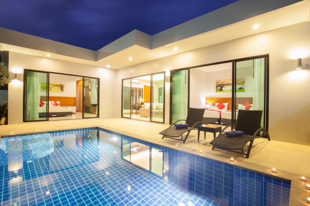 a pool in a house with two chairs and a table at Katerina Pool Villa Resort Phuket in Chalong