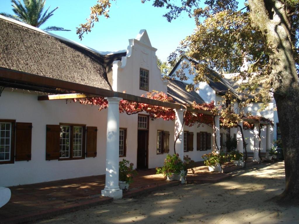 an outside view of a building with trees at Lekkerwijn Historic Country House in Simondium