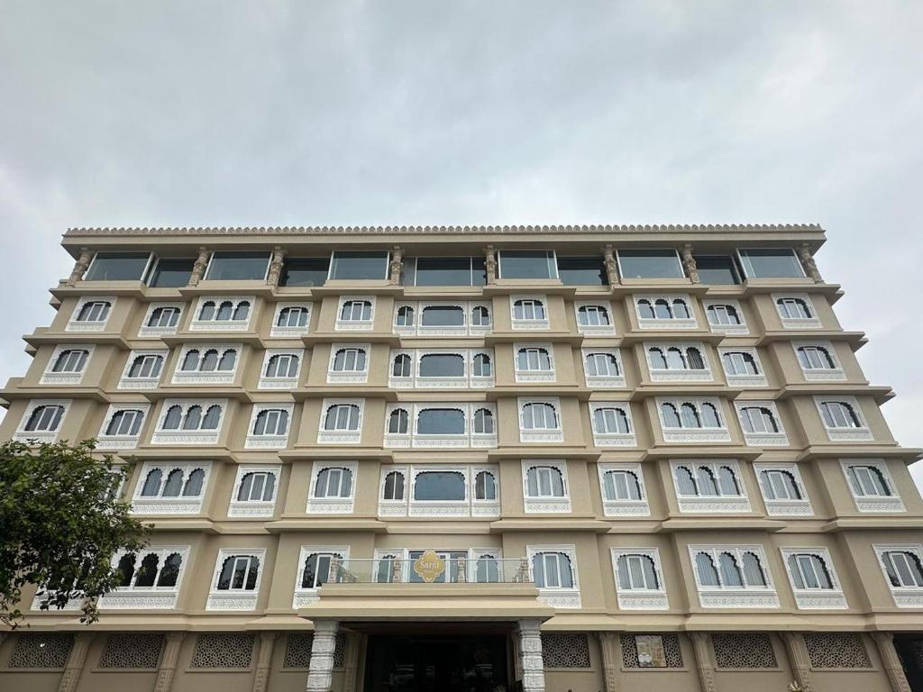 a large building with white windows and a sky at Sarju Palace in Valsād
