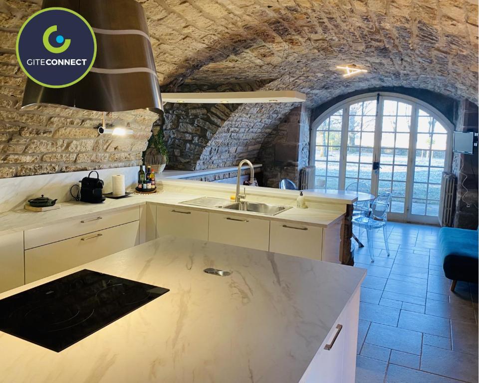 a kitchen with a sink and a stone wall at Le PARC DE LA TRICHERIE in Onet le Château