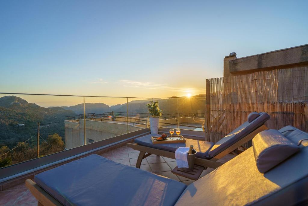 a balcony with a couch and a table and the sunset at Villa Koomas-Mountain View - kakodiki Paleochora in Avdhoulianá