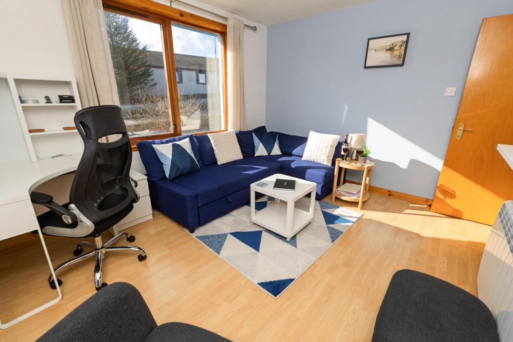 a living room with a blue couch and a chair at Sound House, Shetland Islands in Lerwick