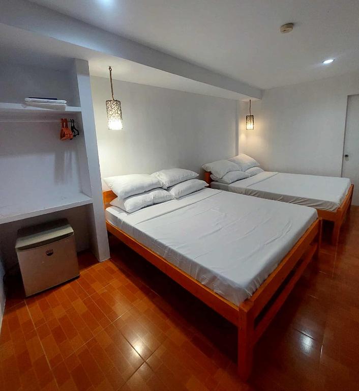 two twin beds in a room with wood floors at RenSea Haven Boracay in Boracay
