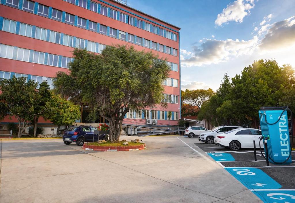 a parking lot with a tree in front of a building at Aparthotel Montcada in Montcada i Reixac