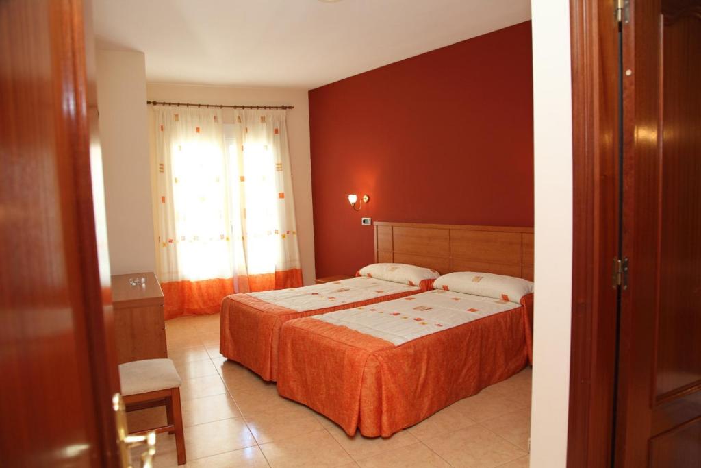 a bedroom with two beds and a red wall at Hotel Ciudad Pozo Alcón in Pozo Alcón