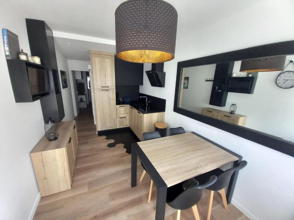 a living room with a dining room table and a kitchen at Un écrin chic à deux pas de la mer in Merlimont