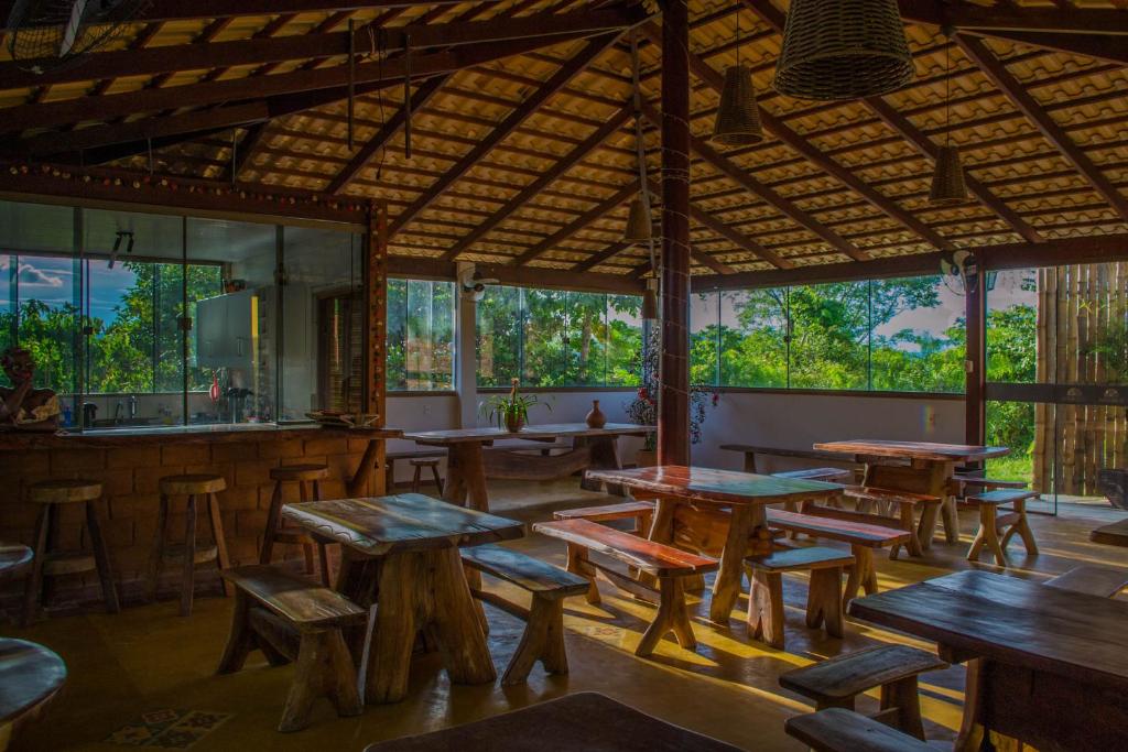 un ristorante con tavoli e sedie in legno e finestre di Chalés Terraviva a Pirenópolis