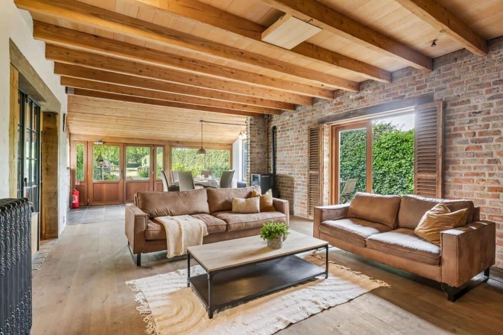 a living room with two couches and a brick wall at Casiola - Authentic vacation home 'De Blauwe Kroon' in Oostkamp