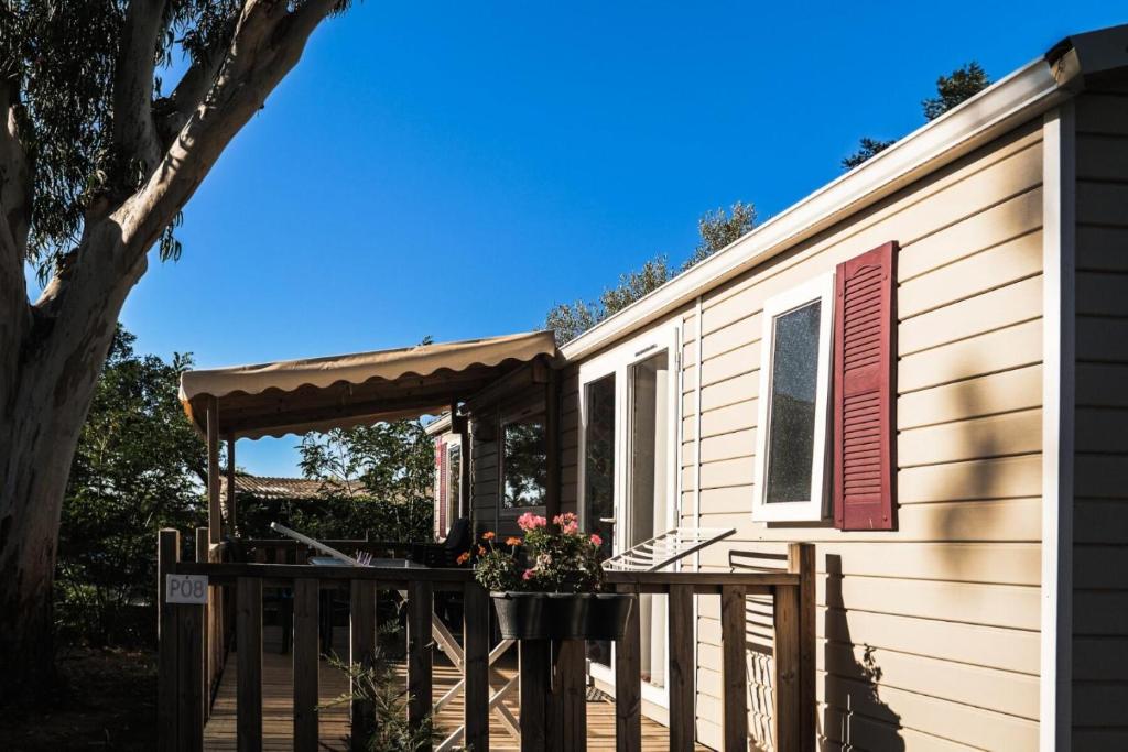 a tiny house with a deck and a pergola at Camping U Pezzo - Mobil home 4 pièces 6/8 personnes Climatisé MAE-2285 in Saint-Florent
