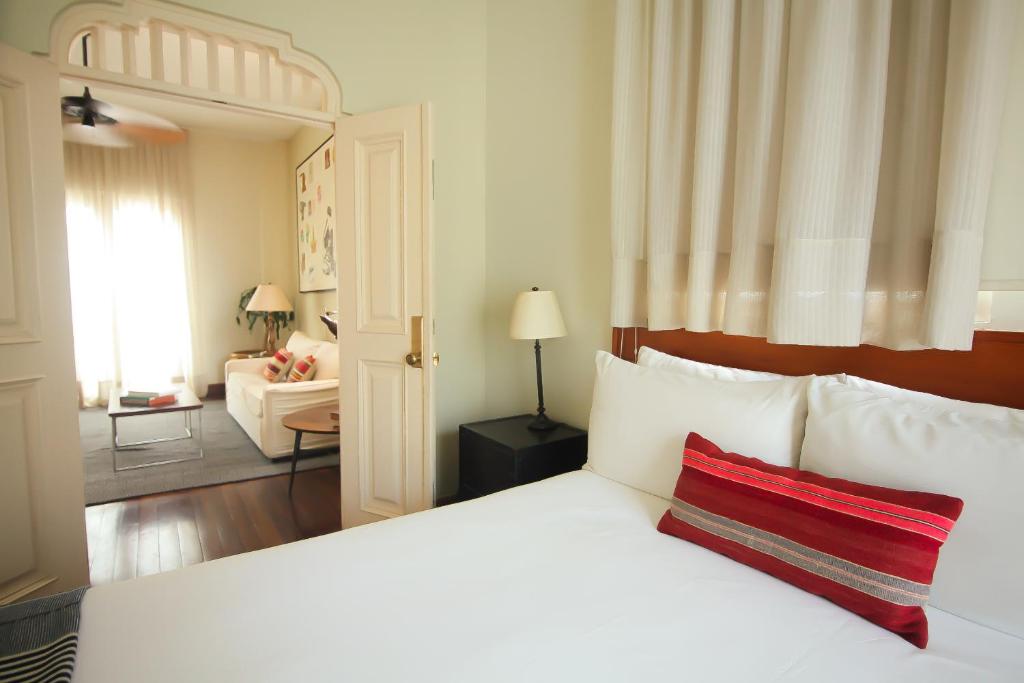 Un dormitorio con una cama blanca con una almohada roja. en Las Clementinas, en Panamá