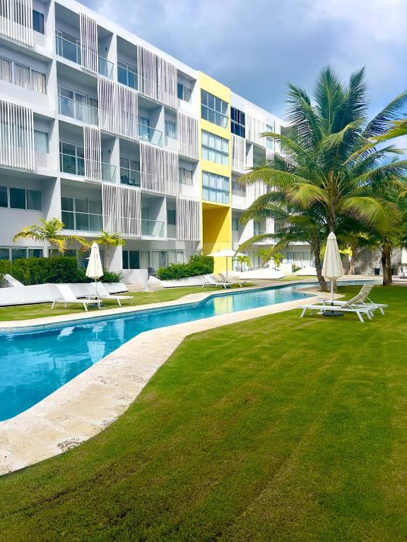 a swimming pool in front of a large building at Downtown Chic Donde inicia la diversión en Punta Cana in Punta Cana
