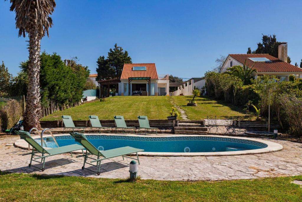a swimming pool with chairs and a house at Casa da Colina, By Home Match in Sesimbra