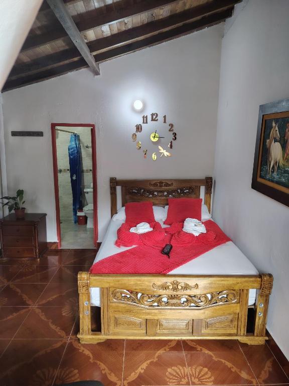 a bedroom with a wooden bed with red sheets at Libélula finca-hotel in Concepción
