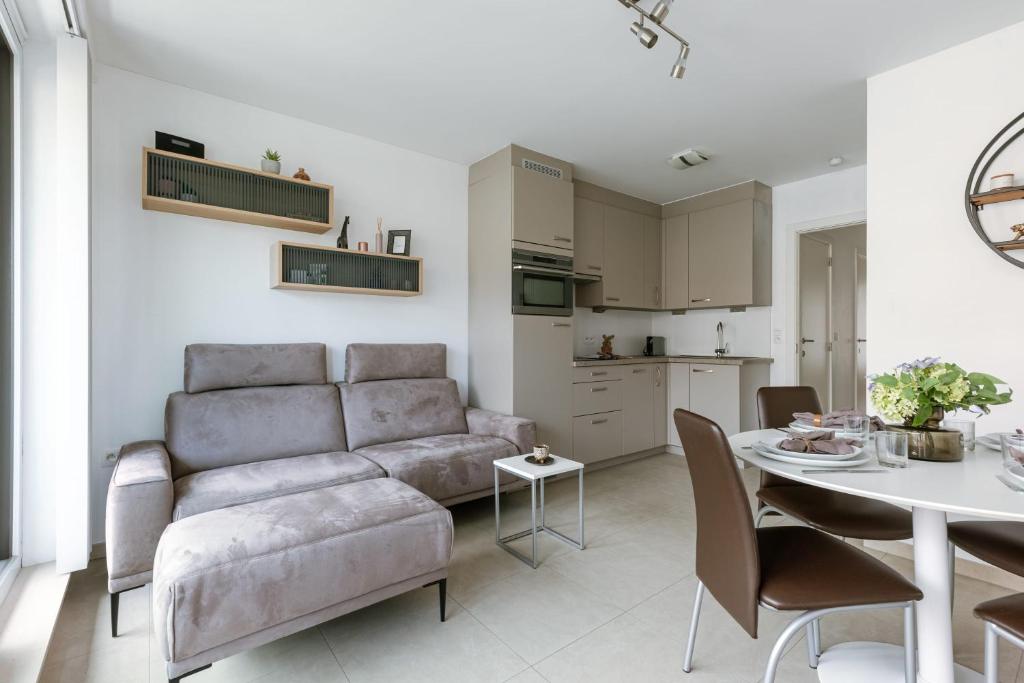 a living room with a couch and a table at Casiola - Spacious & light apartment with double terrace in Nieuwpoort