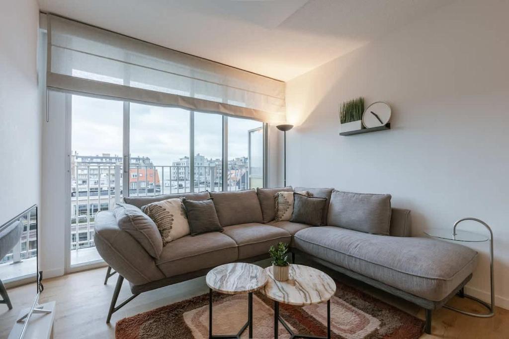 a living room with a couch and a large window at Casiola - Nice apartment close to the beach with parking in Nieuwpoort