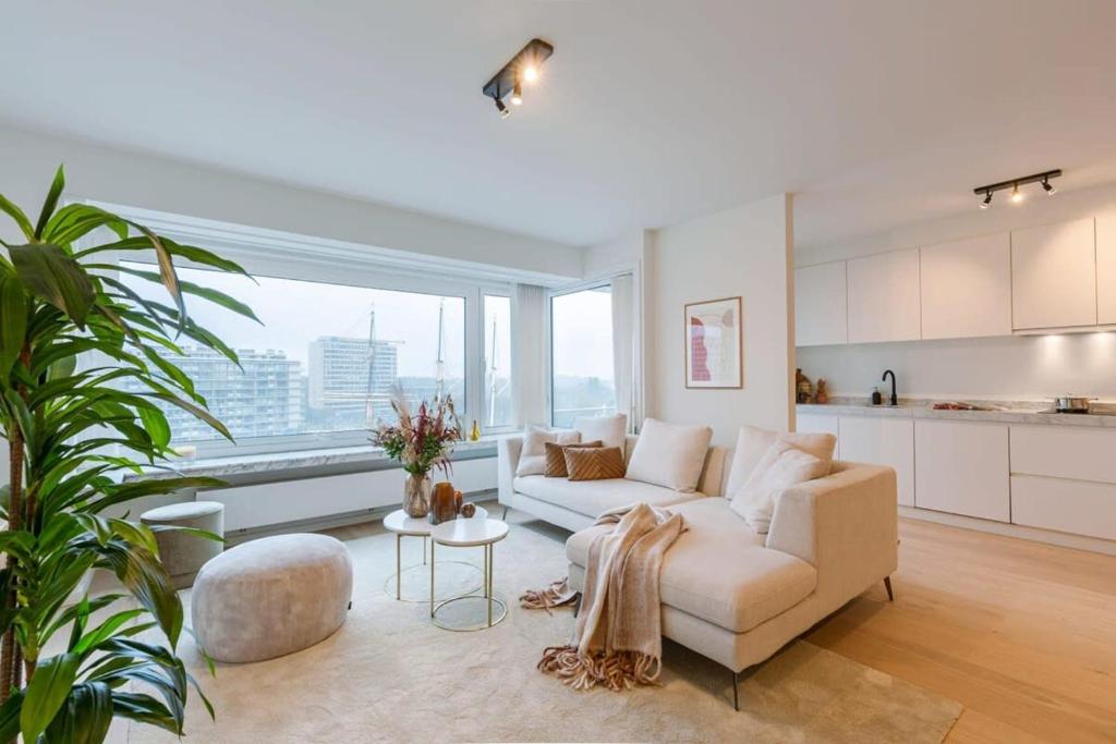 a living room with a white couch and a large window at Casiola - Luminous family apartment with magnificent view in Ostend