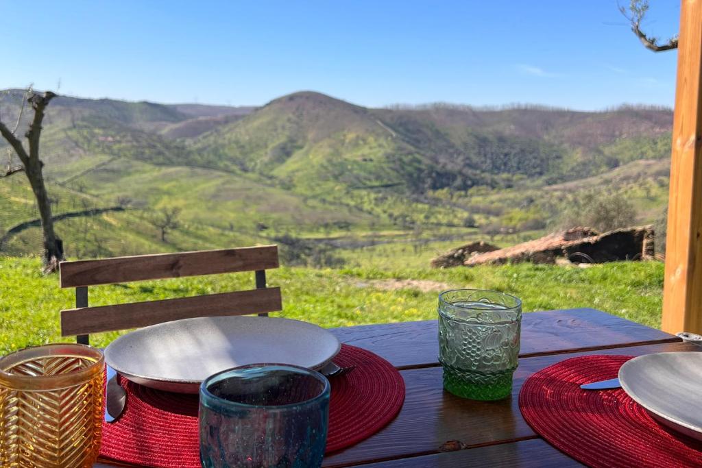 a wooden table with plates and glasses and a view of mountains at Casa da Vinagra in Pé da Serra
