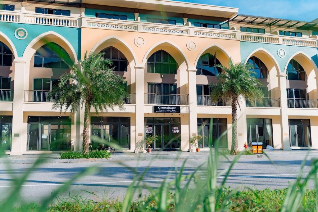 a building with palm trees in front of it at Sonasea Vân Đồn - Centraltique Seaside in Quang Ninh
