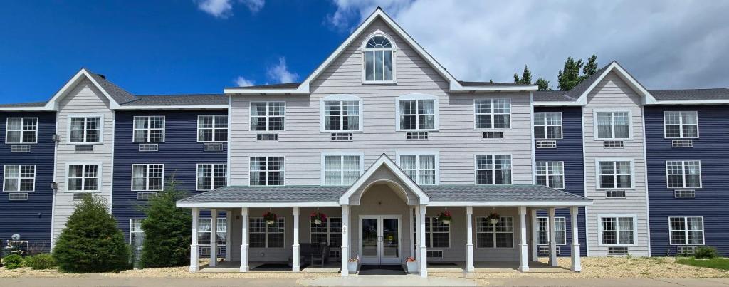 a large house with a large blue building at GrandStay Hotel & Suites Hastings in Hastings