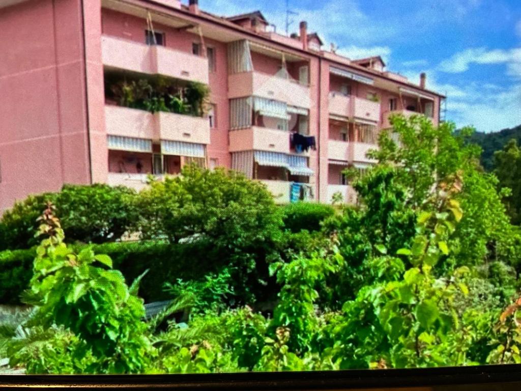 a pink building with trees in front of it at Casa Turistica Andora in Marina di Andora