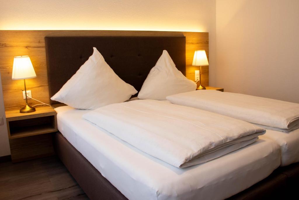 a bedroom with two beds with white sheets and two lamps at Apartments-Altenahr in Altenahr