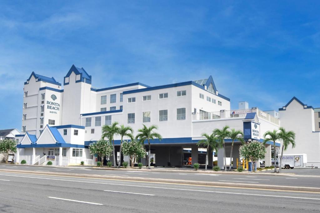 a large white building with palm trees in front of a street at Bonita Beach Hotel in Ocean City