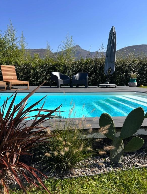 a swimming pool with two chairs and an umbrella at Chambre avec piscine, saison estivale in Urrugne