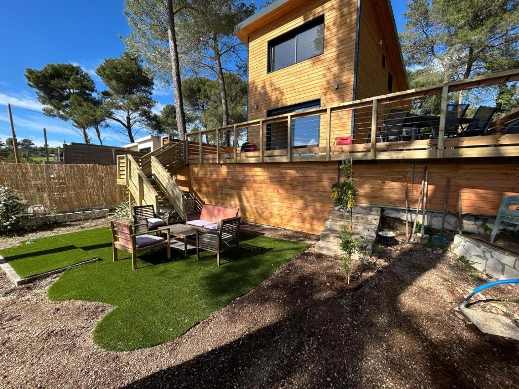 a house with a deck and a lawn with chairs at Chalet Ali Vue panoramique in Le Castellet