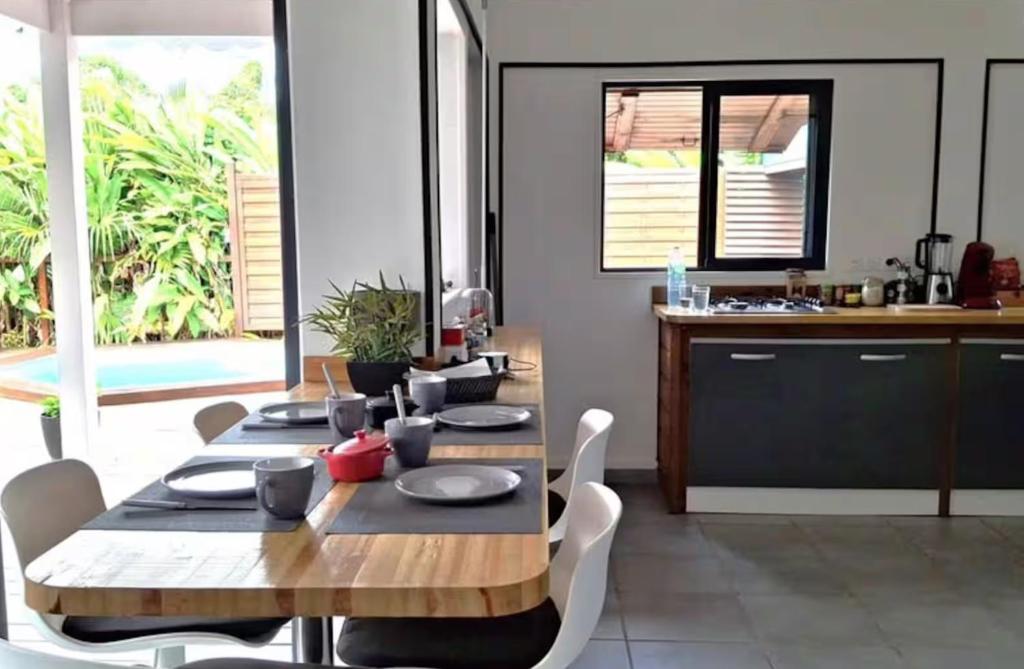 a dining room with a table and a kitchen at Location saisonnière in Petit-Bourg