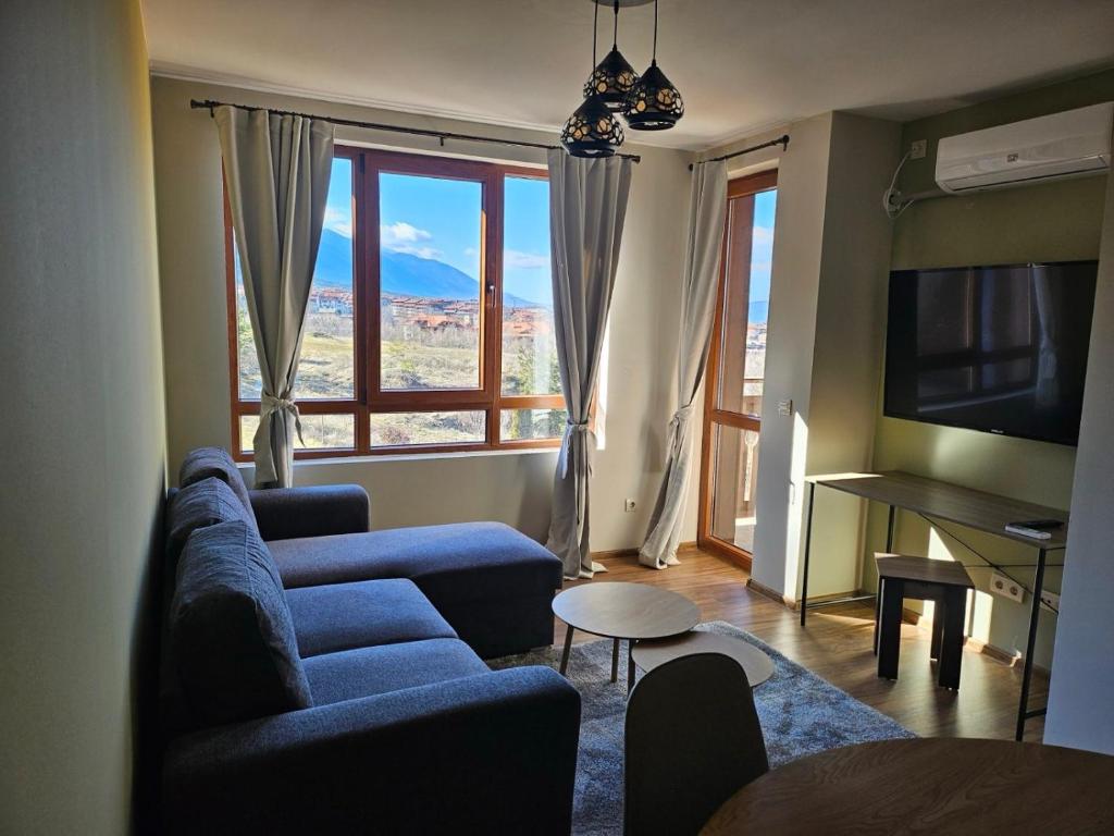 a living room with a blue couch and a large window at Panorama View in Bansko