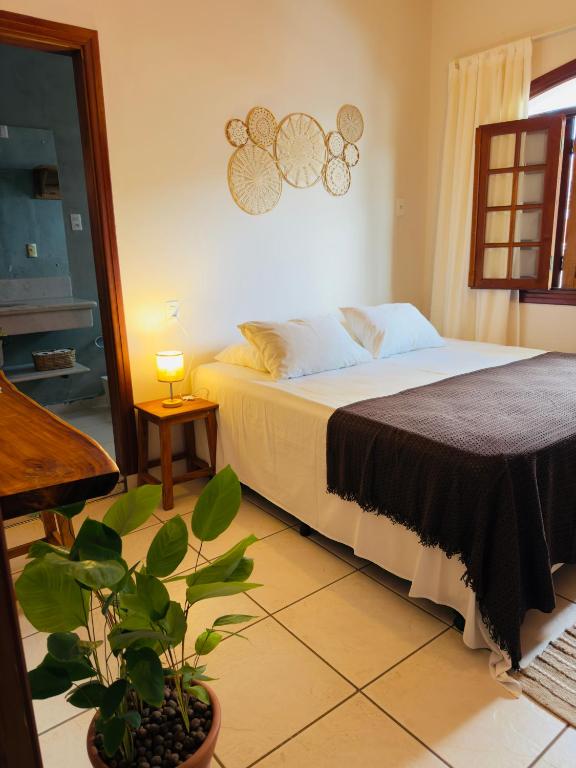 a bedroom with a bed and a potted plant at Jeromia Casa e Pousada in Rifaina