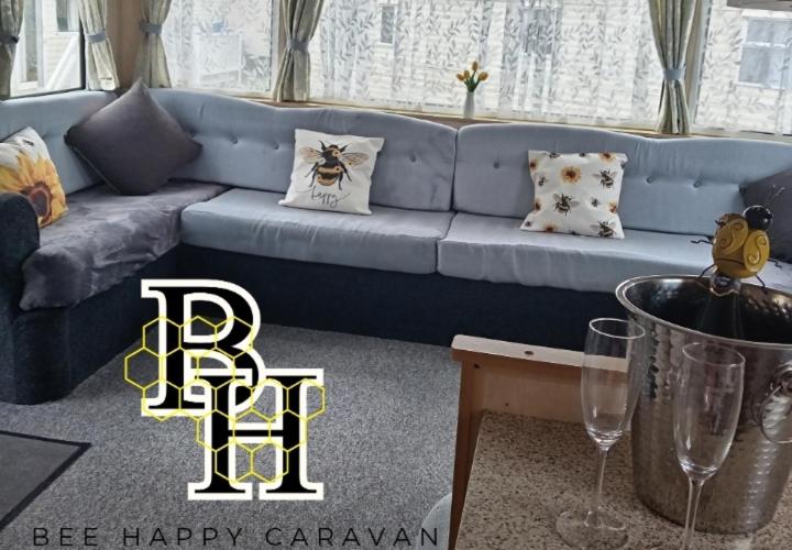 a blue couch in a living room with a bee happy garland at Bee Happy Caravan in Abergele