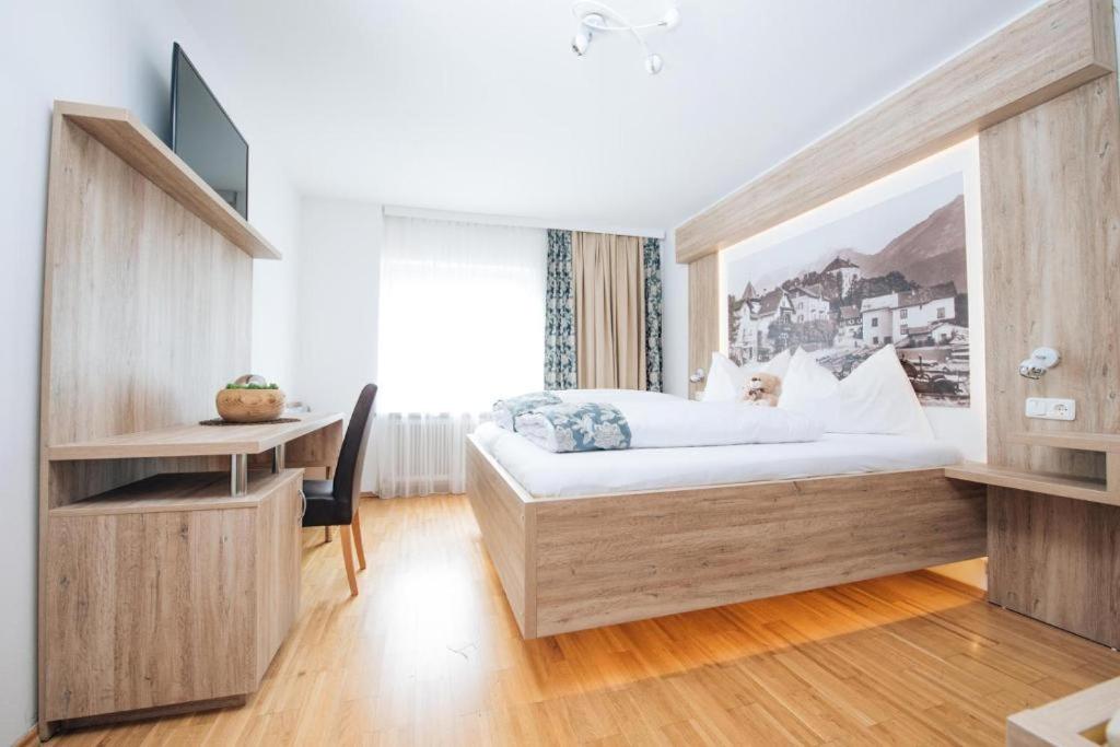 a bedroom with a bed and a desk and a television at Boutique Hotel Adler in Golling an der Salzach