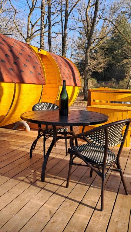 a table and chairs on a deck with a vase on it at Tonneau Bourgignon in Le Rousset