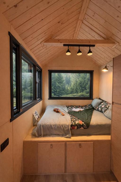 a bed in a tiny house with windows at Tiny House Retreat Mountain View Bicazul Ardelean in Bicazu Ardelean