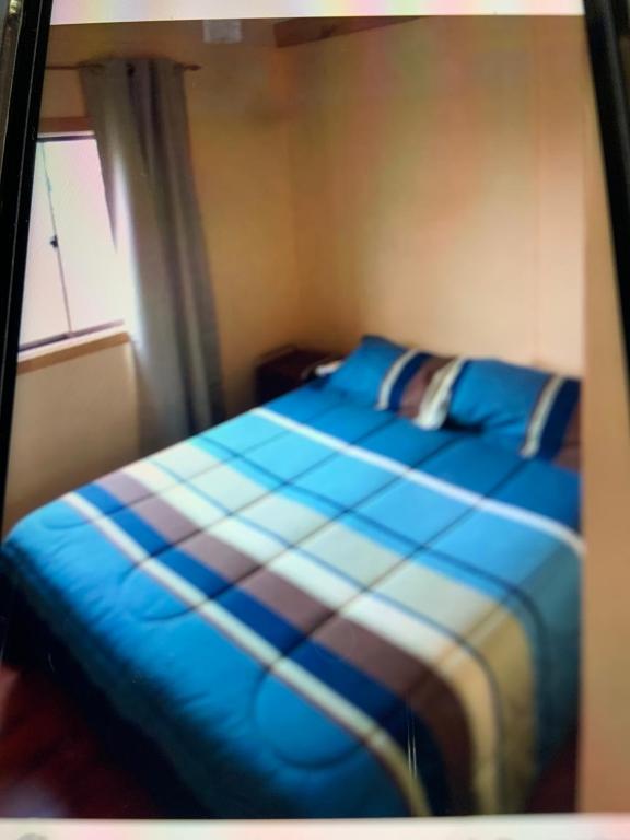 a bedroom with a blue bed with a window at Cabañas río seco in Punta Arenas