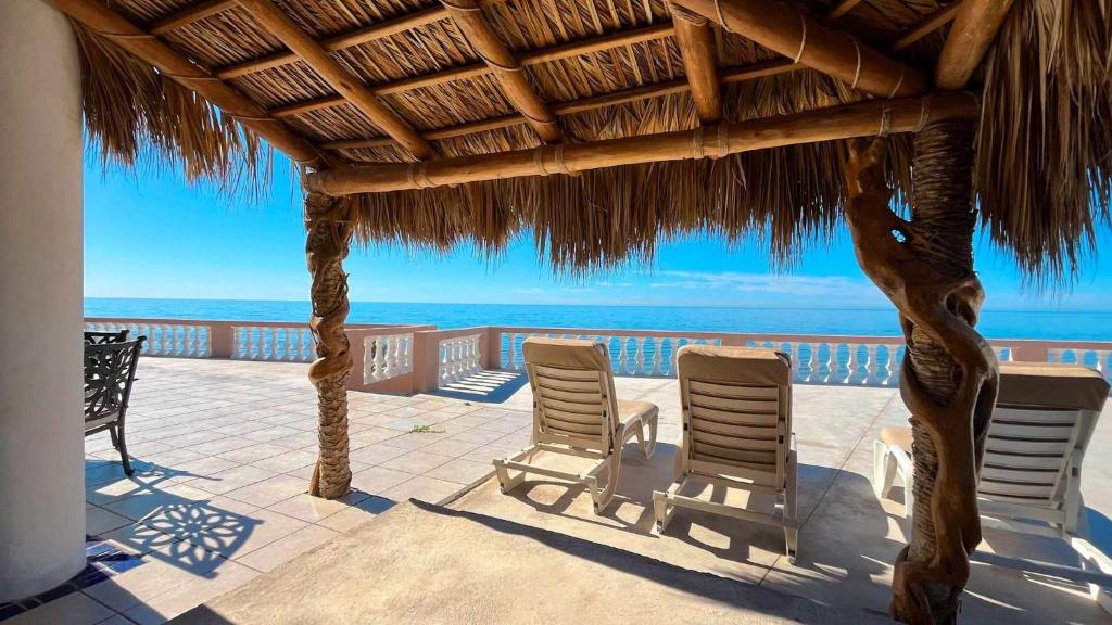 a patio with two chairs and a straw umbrella at Recently Updated Beachfront Home Casa Neblina in Puerto Peñasco