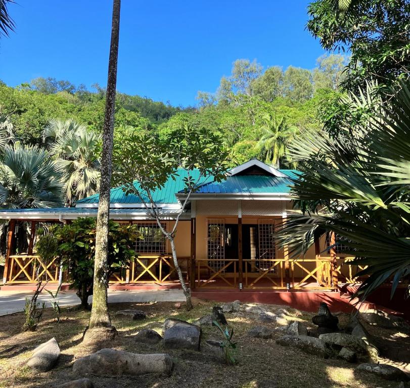 atropical house with a green roof and palm trees at Villa Maria Anse Corail in Takamaka