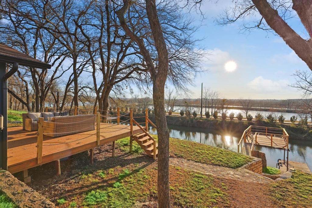 a wooden deck with a bench next to a river at Lake Granbury House, Sleeps 11 with Lake Access! in Granbury