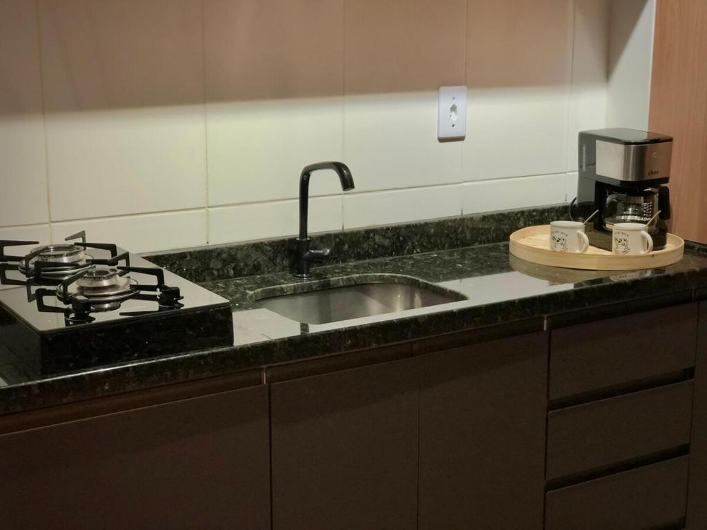 a kitchen counter with a sink and a stove at Studio 406 Paranagua in Paranaguá