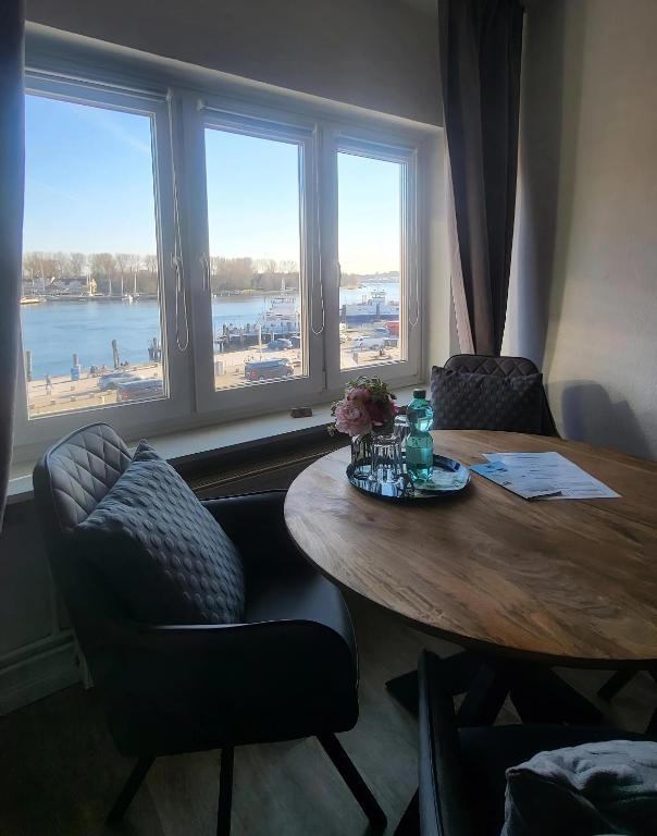 a dining room table with two chairs and a table and windows at Ankerplatz Lichtblick in Travemünde