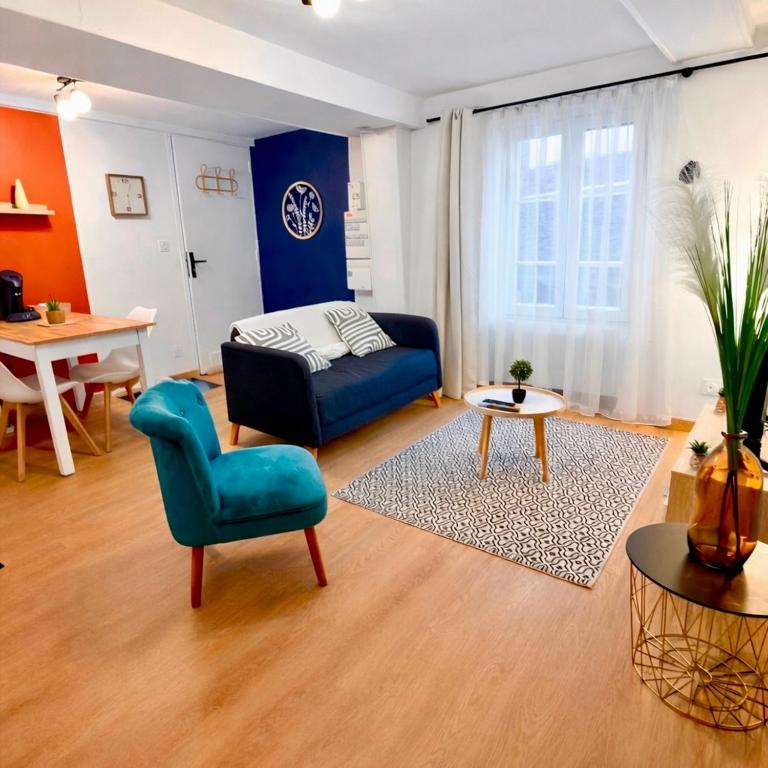 a living room with a blue couch and a table at Le Beau Dolois - Appartement Climatisé au Coeur de DOLE avec Parking GRATUIT à proximité in Dole