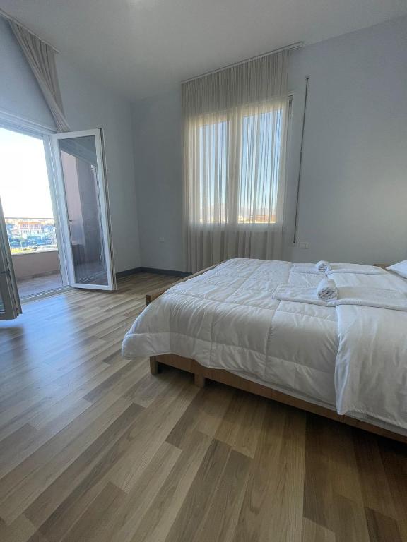 a white bedroom with a bed and a wooden floor at Hotel RADOJA in Shkodër
