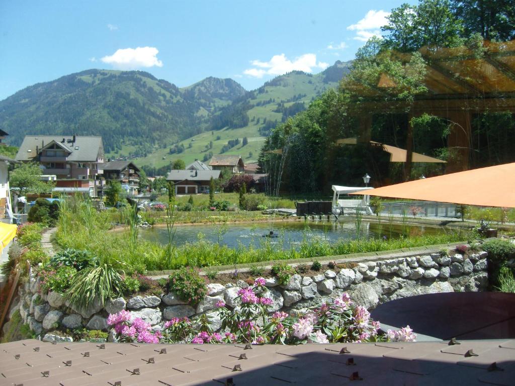 um jardim com flores e uma parede de pedra em Vista Resort Hotel em Zweisimmen