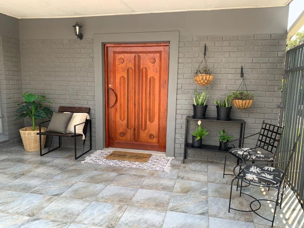 a wooden door on a house with chairs and plants at Cottage @19th in Pretoria