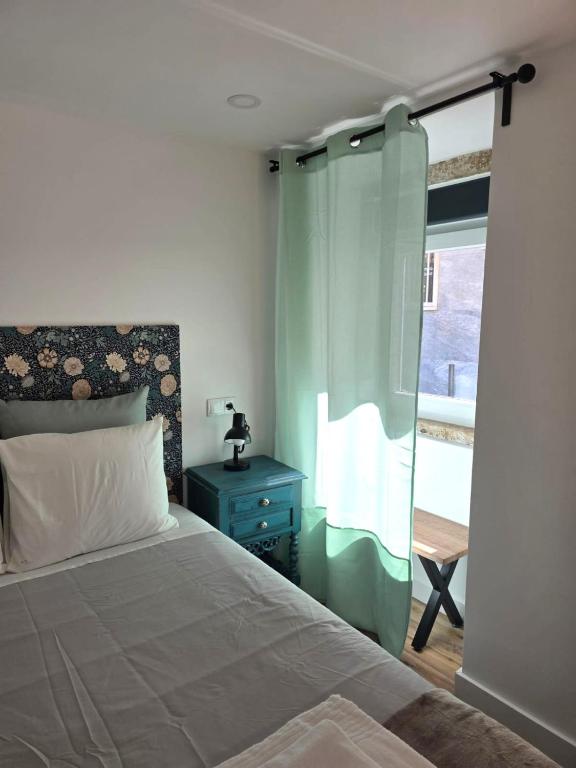 a bedroom with a bed with a blue nightstand and a window at Casinhas da Ajuda nº15 in Lisbon