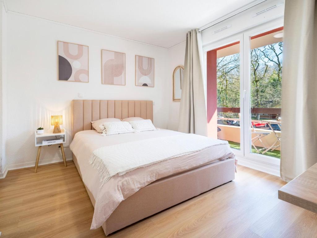 a white bedroom with a bed and a large window at Le doux refuge domaine thermal et activités touristiques Amnéville in Amnéville
