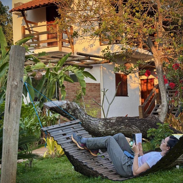 a woman laying in a hammock reading a book at Adega Cipó Pousada Serra do Cipó in Serra do Cipo