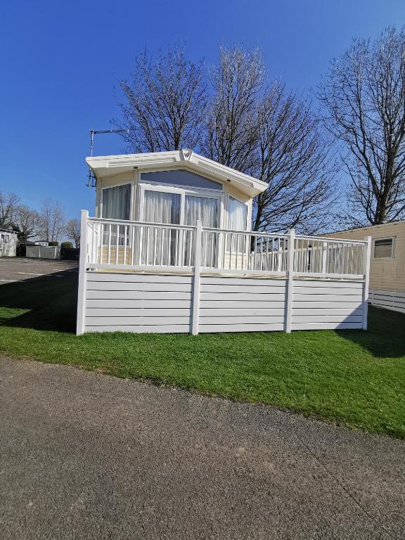 a white house with a fence in the grass at Washbrook Way 2 in Fenny Bentley