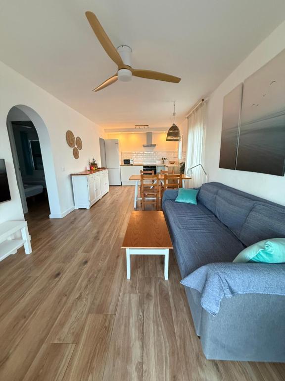 a living room with a blue couch and a table at Ca la Marta apartamento con piscina y jardín a 150m de la playa in Arenal d'en Castell